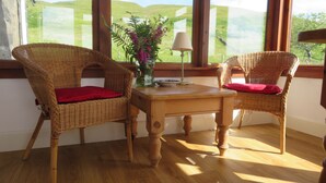 Ein Zimmer mit zwei Korbstühlen, einem Holztisch und einer Blumenvase.