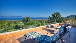 A terrace with two lounge chairs and a view of the sea.
