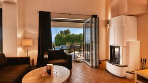 A modern living room with a sofa, a round table, a fireplace, and a view of the outdoors.