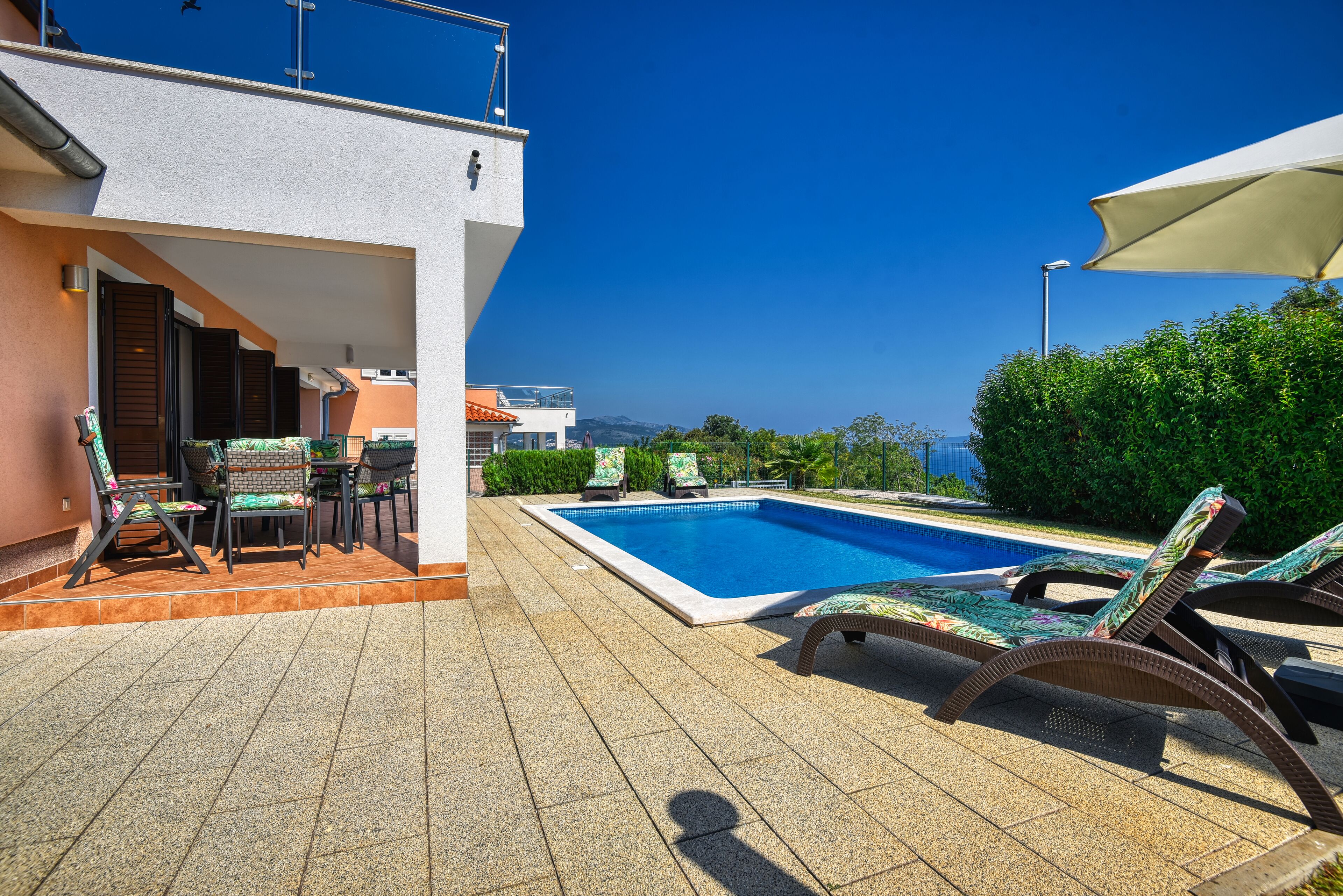 Zona de piscina con sillones de descanso y vistas al mar.