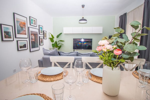 A dining area with a table set for four, surrounded by framed pictures on the wall.