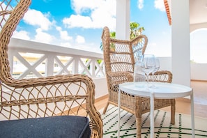 A balcony with wicker furniture, a round table, and two wine glasses.