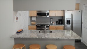 Eine moderne Küche mit Granitarbeitsplatten, Edelstahlgeräten, Holzschränken und Barhocker.