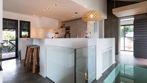 Una cucina moderna con isola in vetro, sgabelli di legno e lampadario a sospensione.
