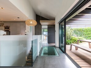 Une cuisine moderne avec des rampes en verre, une terrasse en bois et une vue sur la verdure environnante.