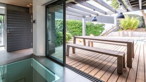 Patio esterno moderno con decking in legno, area vetrata e una panca.
