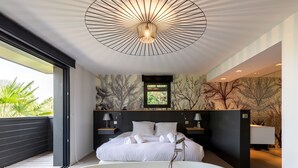 Una camera da letto moderna con un letto grande, una vasca e un lampadario.