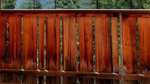 A wooden deck with a view of snow-capped mountains and evergreen trees.