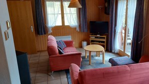 A cozy room with a wooden interior, a sofa, a small table, and a television.