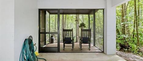A covered outdoor seating area with two chairs and a hose on the left.
