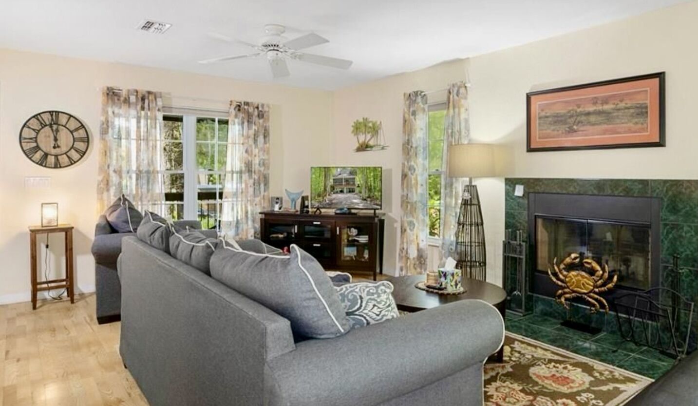 Un salon comprenant un canapé, une cheminée ornée d’un décor en forme de crabe, un téléviseur et une horloge murale.