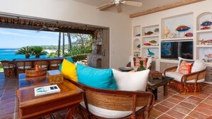 A spacious living area with a view of the beach, wicker furniture, and decorative fish on shelves. - Beachfront Paradise! Please see instructions below prior to booking! (San Jose del Cabo)
