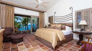 A hotel room with a bed, a chair, a table, and a view of the ocean. - Beachfront Paradise! Please see instructions below prior to booking! (San Jose del Cabo)
