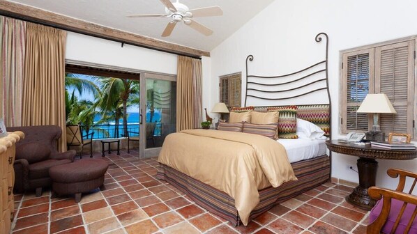 A hotel room with a bed, a chair, a table, and a view of the ocean. - Beachfront Paradise! Please see instructions below prior to booking! (San Jose del Cabo)