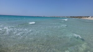 Une plage bordée d’une eau turquoise et limpide, avec une vue lointaine sur la ville.