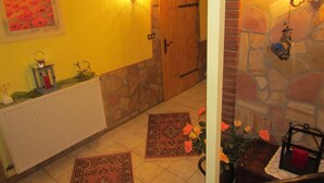 A hallway with a stone wall, a wooden door, a radiator, and a rug. - well-equipped apartment in a quiet forest location (Ramberg)