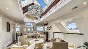 Un vaste espace de vie doté de hauts plafonds, d’un lustre et de plusieurs coins salon.