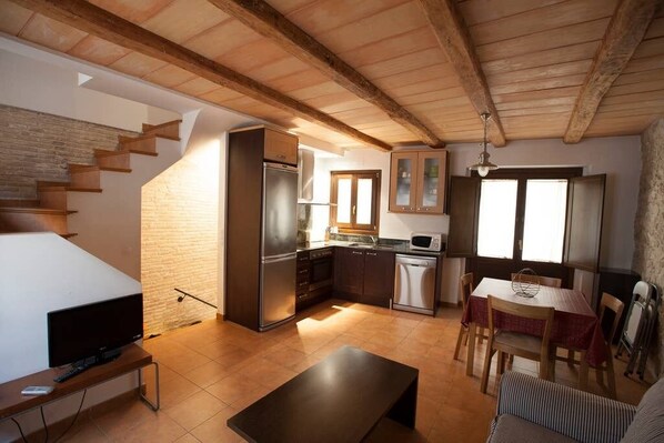 A compact living space with a kitchen, dining area, and a staircase leading to another level.