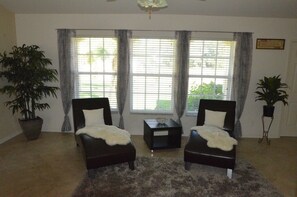 Relax in this serene living space with a large window, ceiling fan, and comfortable seating area.