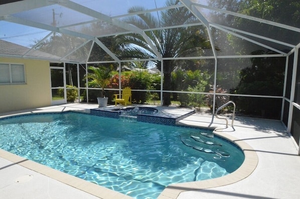 Relax by the pool surrounded by lush greenery and a beautiful deck.