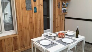 Une pièce aux murs lambrés, avec une table dressée pour quatre personnes, une bouteille et une petite bibliothèque.