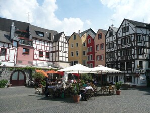 Ein traditioneller europäischer Innenhof mit Steinpflasterung, Gartenmöbeln und bunten Fachwerkhäusern.
