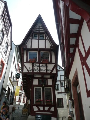 Ein traditionelles Fachwerkhäuschen mit einem Schild, auf dem "Weinstube Spitzhauschen" steht.