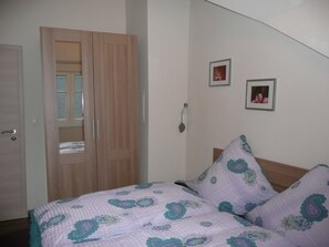 Ein Schlafzimmer mit einem Bett, einem Kleiderschrank und zwei gerahmten Bildern an der Wand.