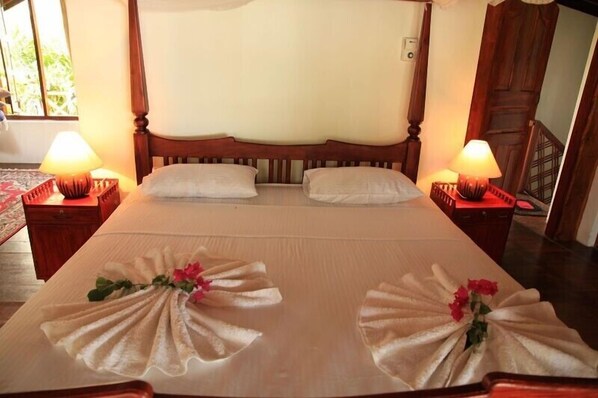 A neatly made bed with two pillows, a wooden headboard, and two bedside lamps. - Peaceful position with a 13meter fresh water swimming pool (Tangalla)