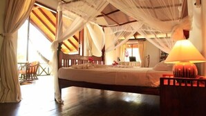 Quarto com cama de dossel, piso de madeira e luminária de cabeceira.
