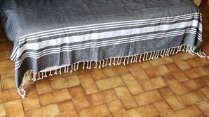 A grey sofa with striped throw, grey cushions, and a white lace pillow.
