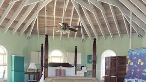Amplia sala de estar con techo alto, ventilador de techo, un sofá grande, una mesa de centro y un otoman en forma de tortuga.