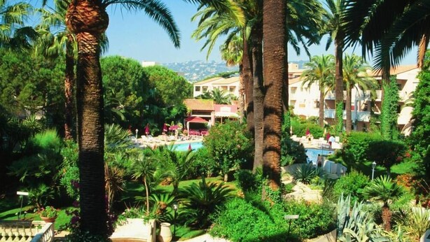 Um resort com palmeiras, piscina e vista para as montanhas.