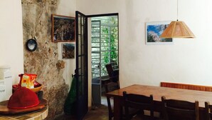 Ein Essbereich mit Holztisch und -stühlen, einer Steinwand und Blick ins Grüne.