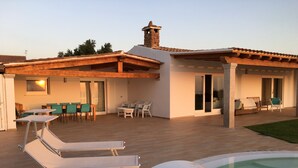 A modern house with a patio, outdoor seating, and a swimming pool.