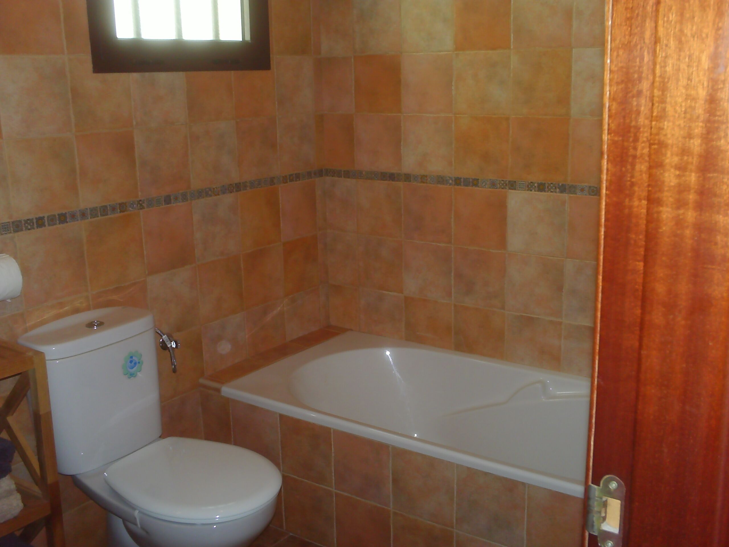 Un baño con inodoro, bañera y paredes de azulejos.
