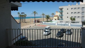 A parking lot with several cars, a building with balconies, and a beach in the background. - Apartment/ flat - Coma-ruga El Vendrell (Coma-Ruga)