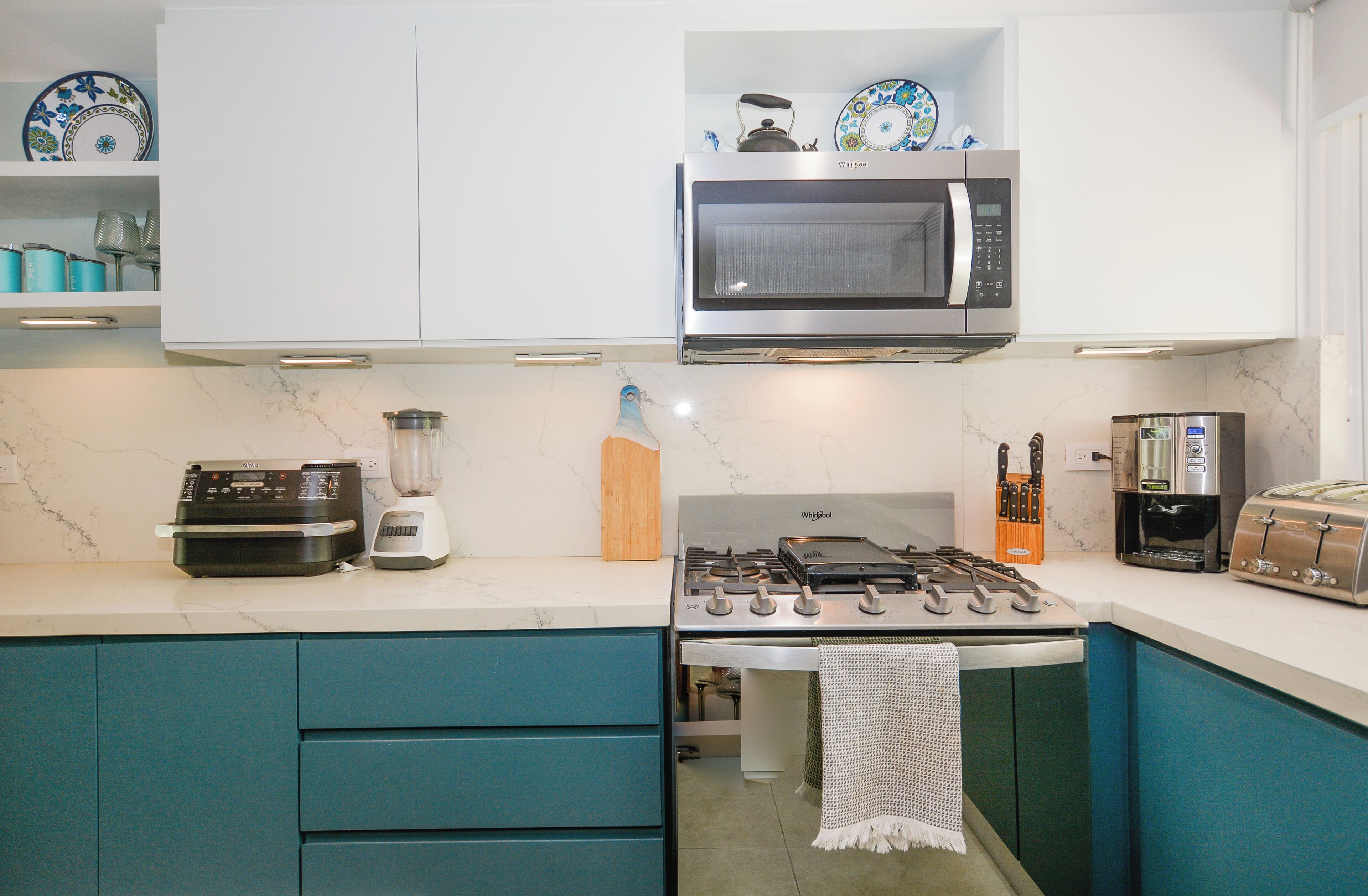 A kitchen with a microwave, toaster, blender, and stove.