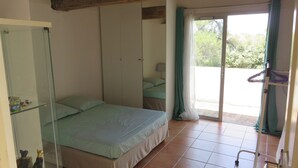 A bedroom with a bed, a glass cabinet, a sliding door to a balcony, and a window with curtains.