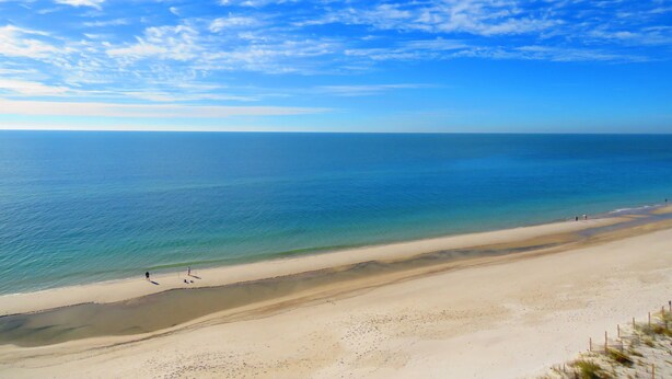 Een strand met heldere lucht en rustig water.