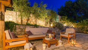 An outdoor seating area with a stone wall, wooden furniture, and lanterns.