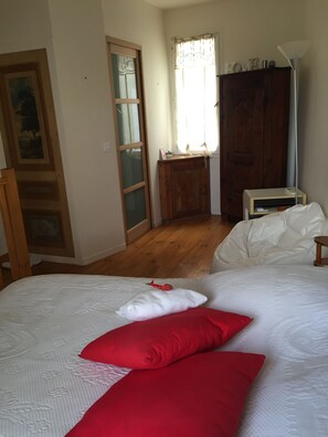 A bedroom with a bed, a wooden wardrobe, a nightstand, and a window with curtains.