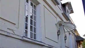 A building with a light-colored facade, a set of concrete steps leading up to a door, and a small garden area with white flowers. - Beautiful 16th century house (Saumur)