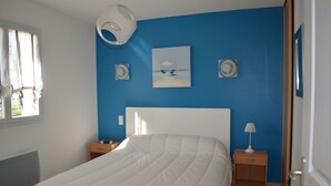 Ein Schlafzimmer mit einem weißen Bett, einer blauen Akzentwand, einem Gemälde und zwei Nachttischen mit Lampen.