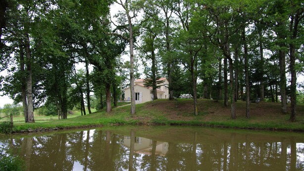 Ein Haus, umgeben von Bäumen und einem Teich.