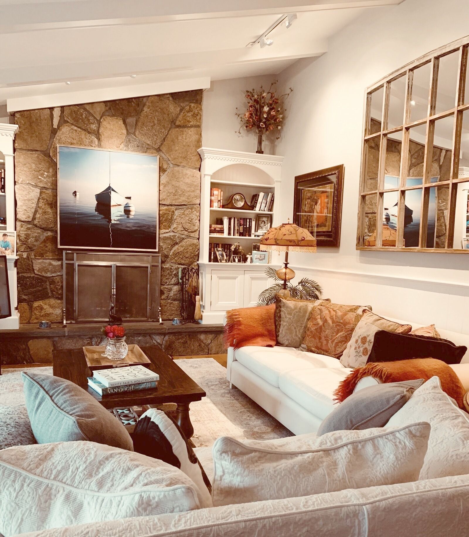 A living room with a stone wall, a flat-screen TV, a bookshelf, and a window with a view.