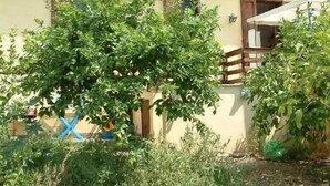 A building with a yellow facade, wooden balconies, and lush greenery in front. - Cottage in the lemon grove on the sea (Lido di Noto)