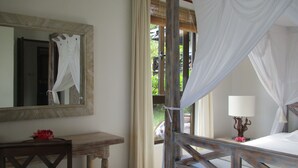 Une chambre à coucher avec un lit en bois, une table de chevet avec une lampe, un miroir et une vue sur la verdure à l’extérieur.