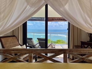 Enjoy ocean views from the large window, featuring a comfortable bed and lounge chairs.