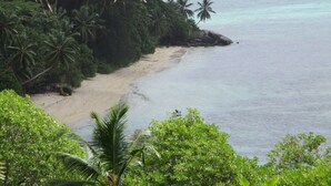 A beach with clear turquoise water, sandy shore, and lush green vegetation. - Chalets Bougainville
Ground floor Apartment with Ocean View (Bougainville)